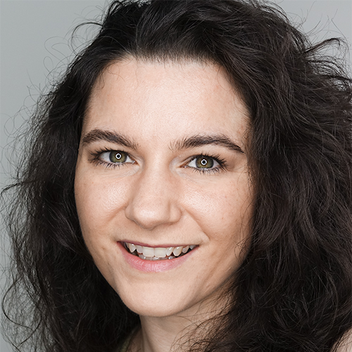 Actor, voiceover artist and streamer, Nina Nikolic's headshot. Woman with long, brown curly hair smiling at the camera.