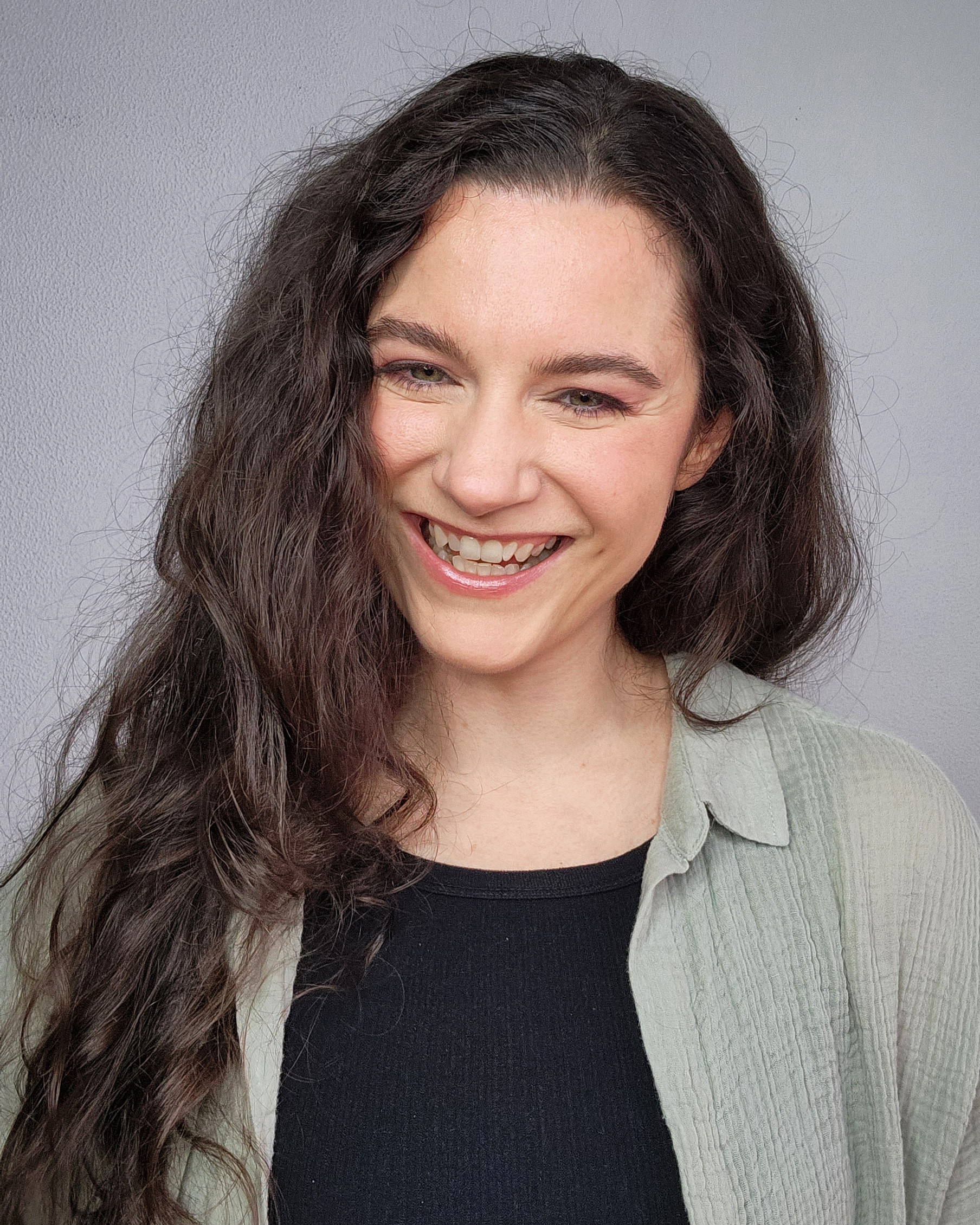 Woman with long, curly brown hair smiling.