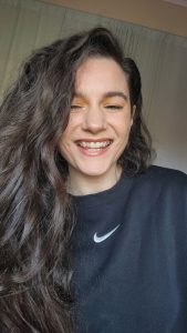 Smiling working actor in a relaxed, performance-ready training moment, wearing a black Nike sweatshirt, showcasing the lifestyle of a voice actor who embraces authenticity and joy in her daily routine.